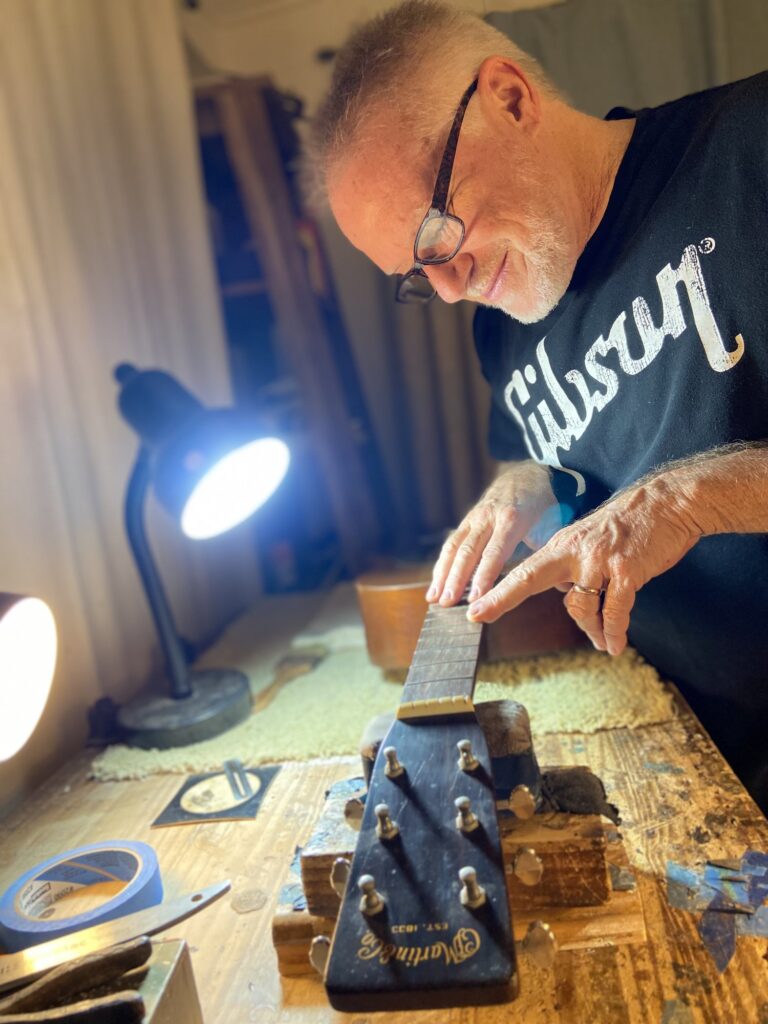 guitar repairman working on a guitar neck